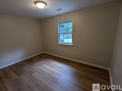 A room with wooden flooring and a window.