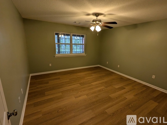A room with wooden flooring and a window with blinds.