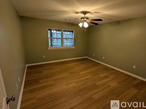A room with wooden flooring and a window with blinds.