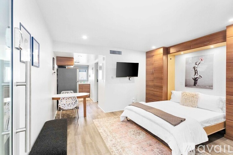 A bedroom with a large bed and a television mounted on the wall.