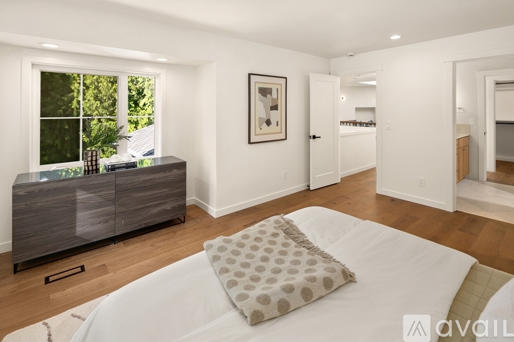 A bedroom with a large bed and a window overlooking a green area.