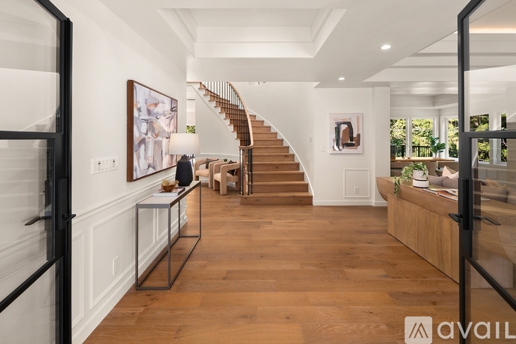 A spacious hallway with a staircase and a glass railing.