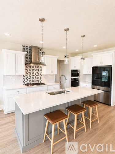 A kitchen with white cabinets and a large island with a sink and three stools.