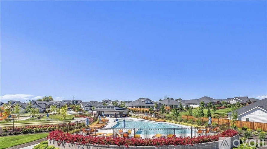 A pool surrounded by red flowers and a clear blue sky.
