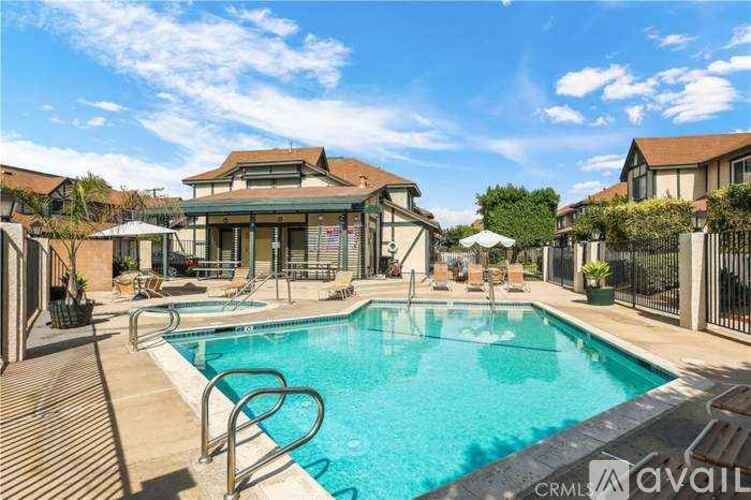 A large outdoor swimming pool surrounded by a deck and lounge chairs.