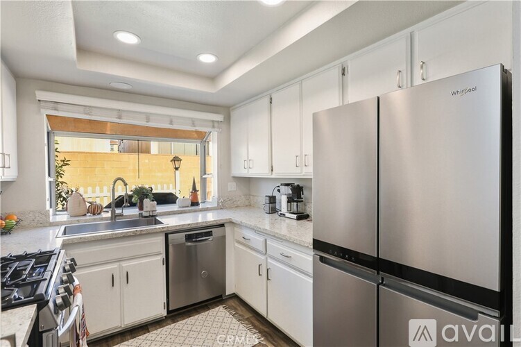 A kitchen with white cabinets and a Whirlpool refrigerator.