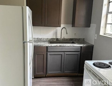 A kitchen with a white refrigerator, brown cabinets, and a white stove.