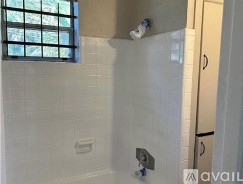 A bathroom with a white tiled shower and a window.