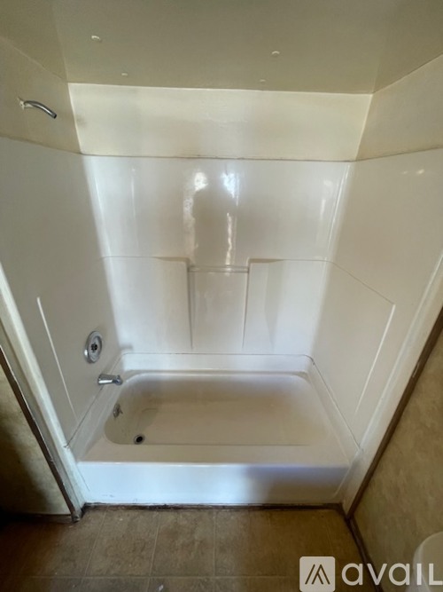 A white bathtub in a bathroom with a brown floor.