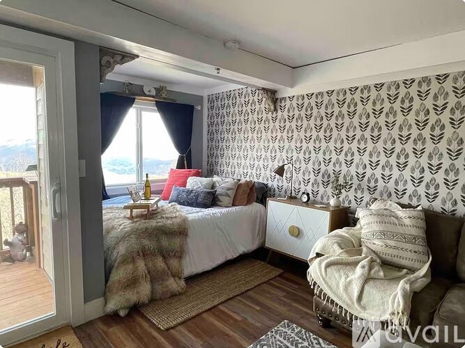 A bedroom with a bed, a couch, and a window with curtains.