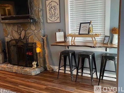 A living room with a stone fireplace and a wooden table with a bottle on it.