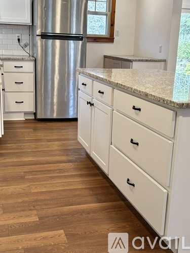 A kitchen with a stainless steel refrigerator and white cabinets.