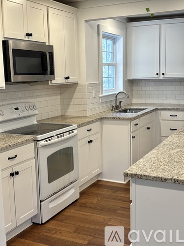 A kitchen with white cabinets and a granite countertop.