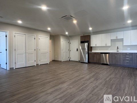 A spacious kitchen with white cabinets and a wooden floor.