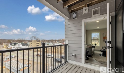 A balcony with a view of a parking lot and buildings.