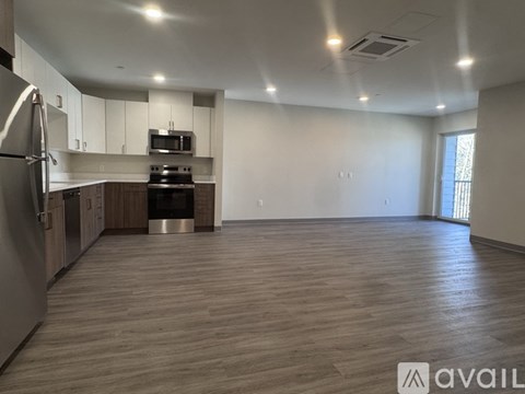 A spacious kitchen with wooden flooring and stainless steel appliances.