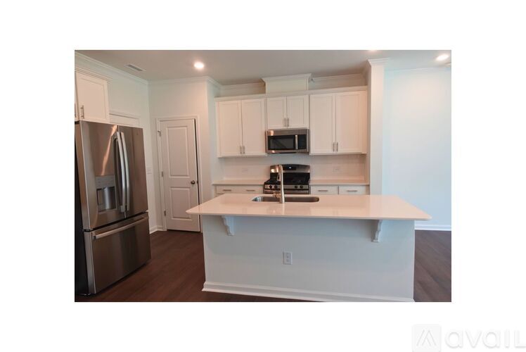 A kitchen with a stainless steel refrigerator, microwave, and white cabinets.