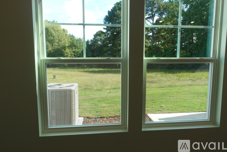 A window with a view of a green lawn and trees.