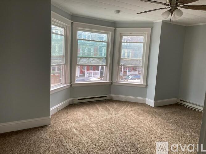 A room with a carpeted floor and a ceiling fan.