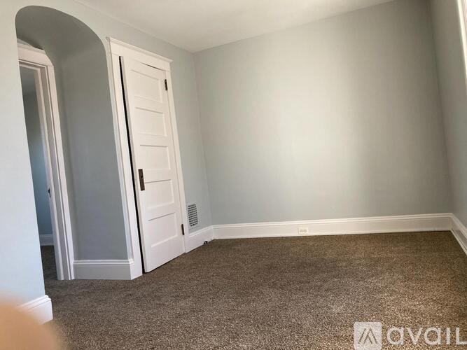 A carpeted room with a white door and a window.