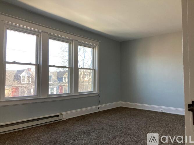 A room with a carpeted floor and a window overlooking a residential area.