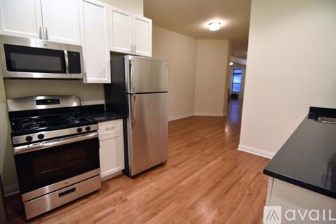 A kitchen with a stove top oven, microwave, refrigerator, and cabinets.
