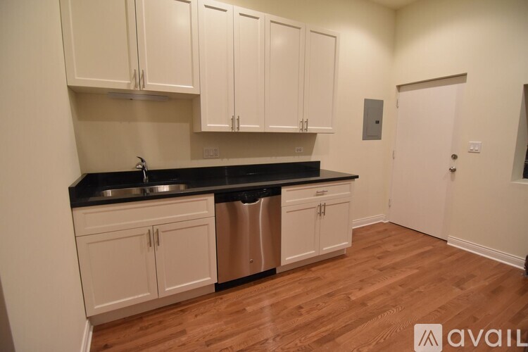 A kitchen with white cabinets and a black countertop.