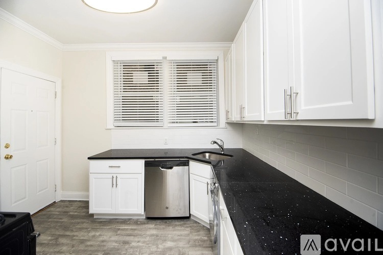 A kitchen with white cabinets and a black countertop.