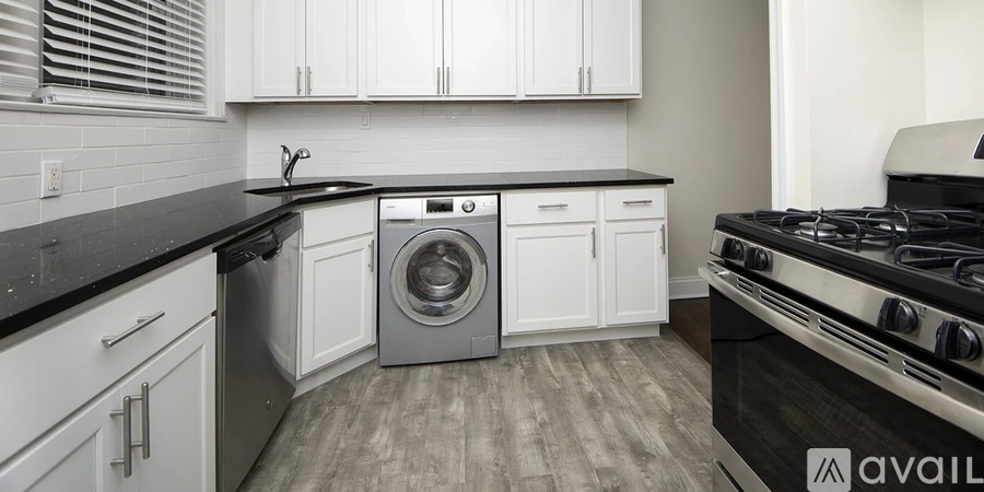 A modern kitchen with white cabinets and black countertops.