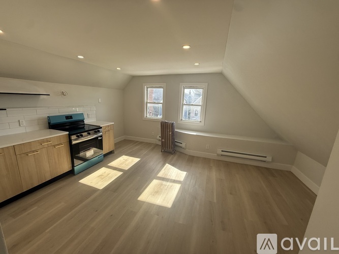 A spacious attic room with wooden flooring and a window.