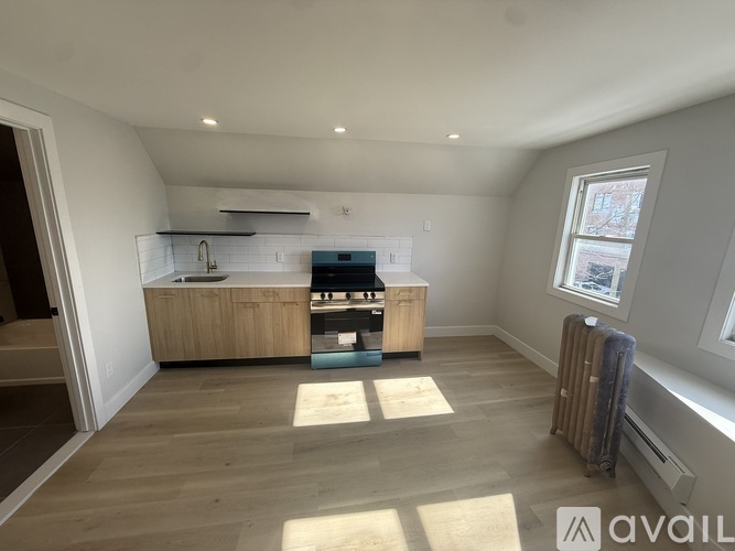 A spacious room with a kitchenette and a window.