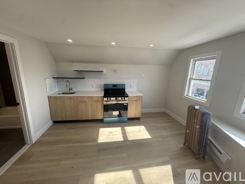 A spacious room with a kitchenette and a window.