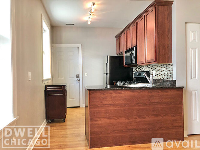 A kitchen with a black fridge and brown cabinets.