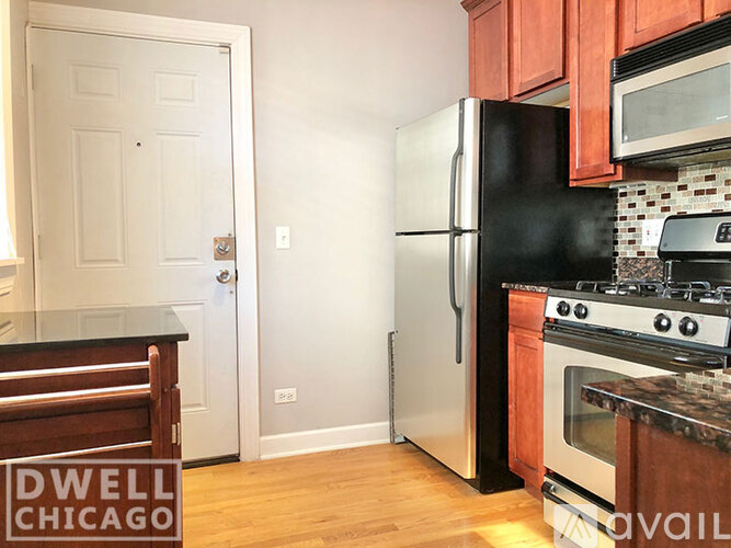 A kitchen with a black refrigerator and stove top oven.
