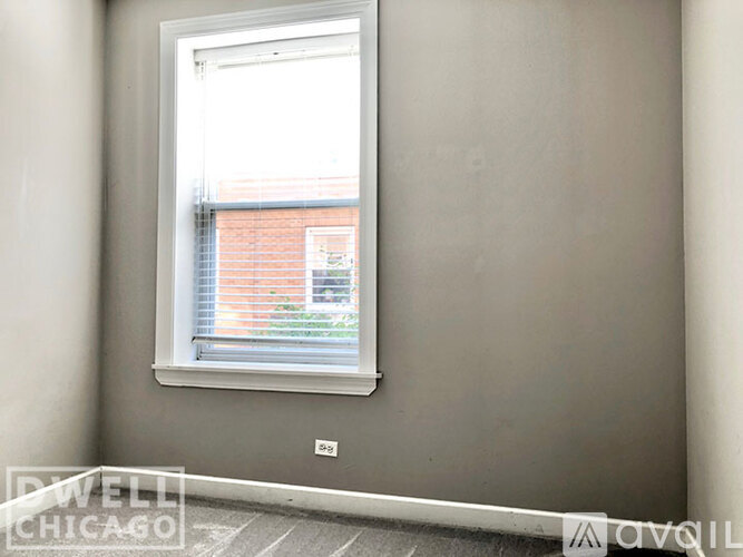 A window in a room with a view of a brick building outside.