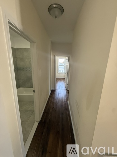 A long hallway with wood floors and white walls.