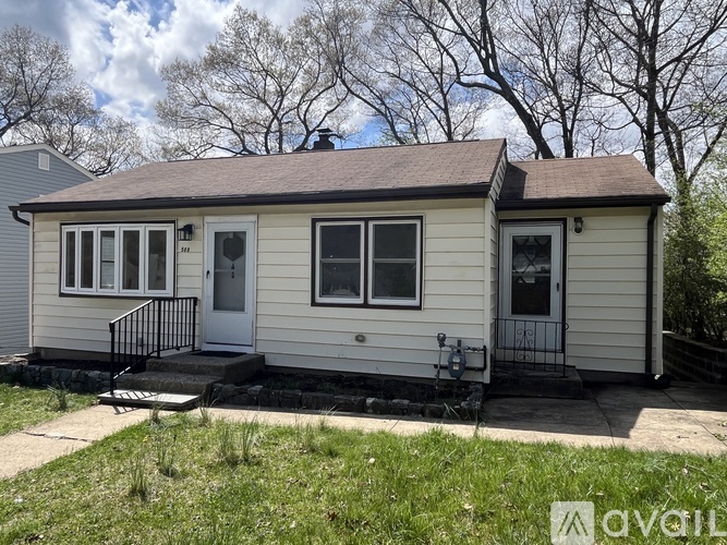 A small house with a white door and a black railing on the porch.