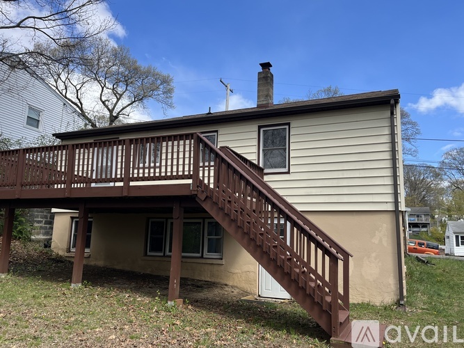 A house with a brown deck and stairs leading to the front door.