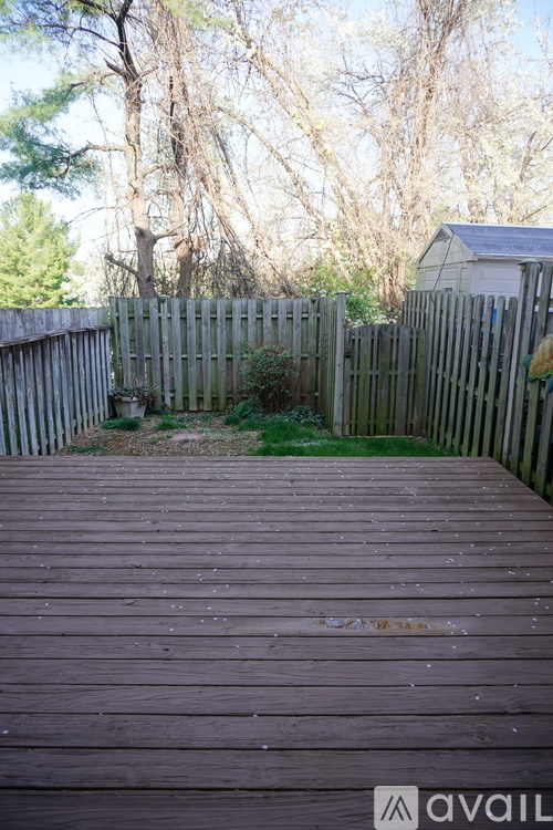 A wooden deck leads to a backyard with a fence and trees.
