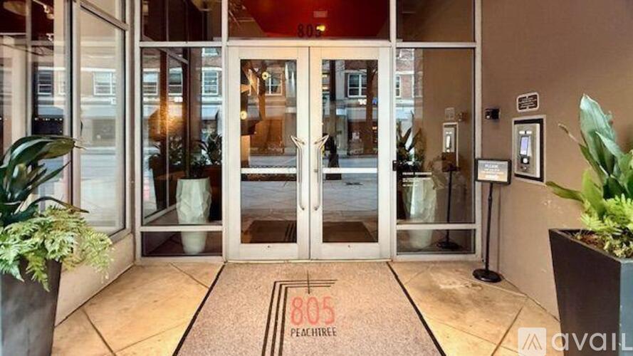 The entrance to a building with a glass door and a doormat that reads 805 Peachtree.