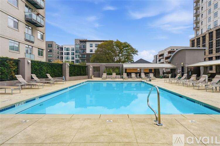 A large outdoor swimming pool surrounded by lounge chairs and buildings.