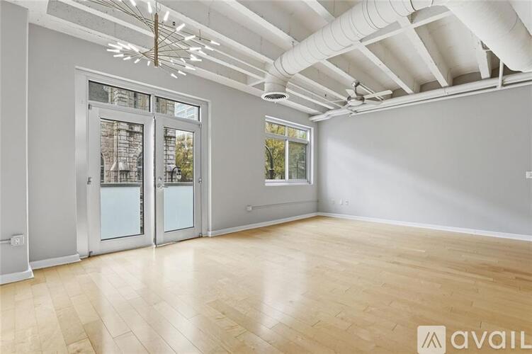 A spacious room with wooden flooring and a large window.