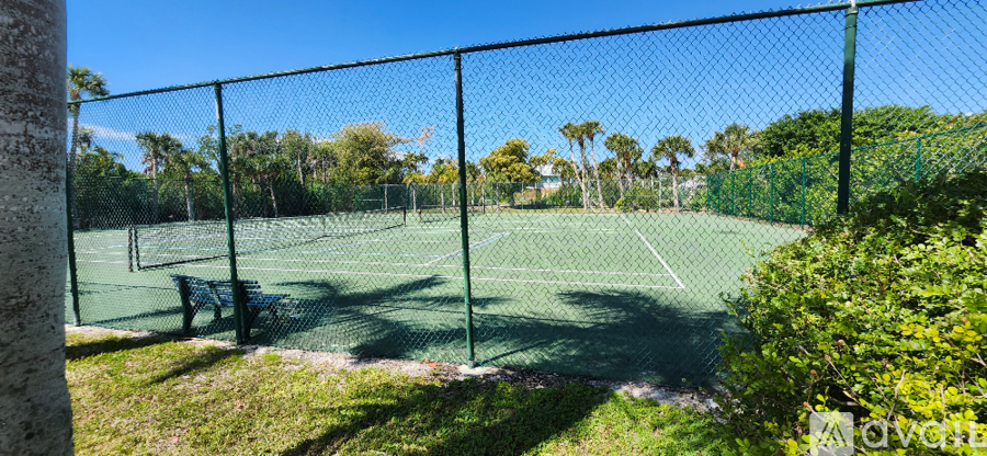 A tennis court surrounded by a fence and trees.