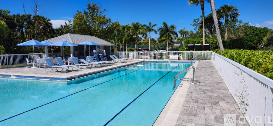 A pool with a white fence and a canopy of umbrellas.