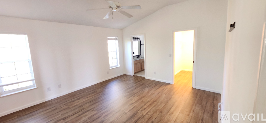 A spacious room with wooden floors and a ceiling fan.