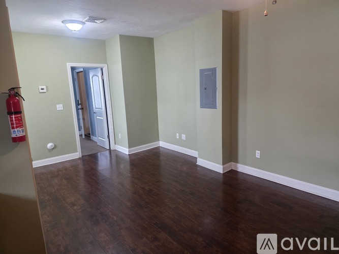 A room with a wooden floor and a fire extinguisher on the wall.