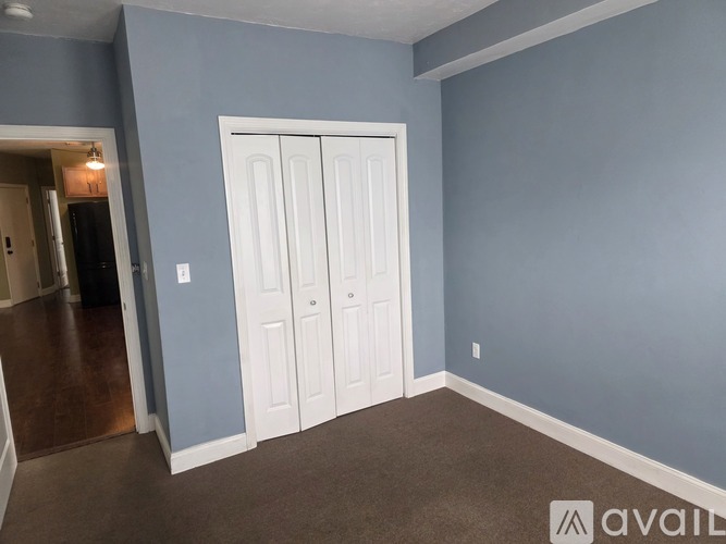 A room with a white door and a carpeted floor.