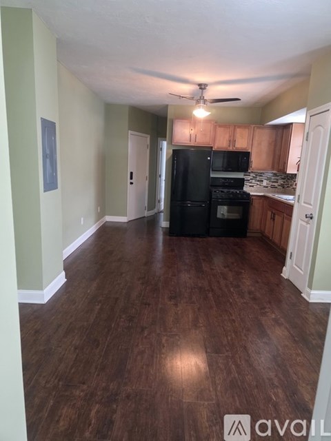 A kitchen with black appliances and wooden floors.