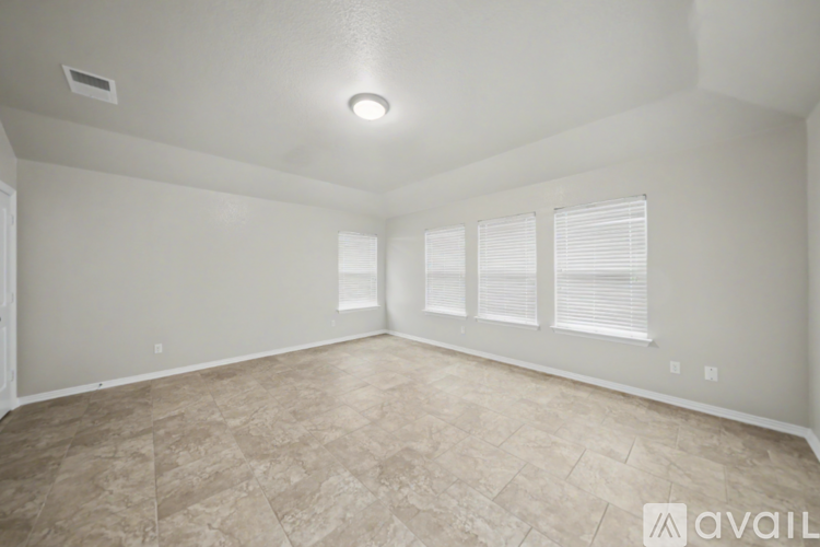 A spacious room with tiled flooring and a single window with blinds.
