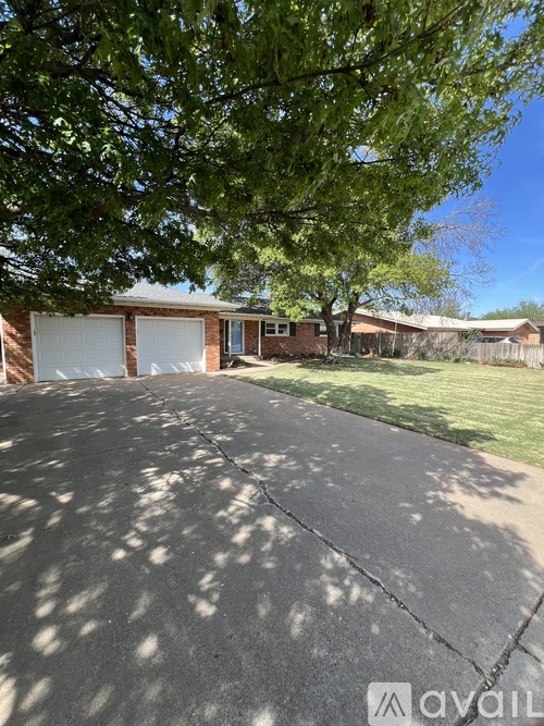A house with a driveway and a tree in front.